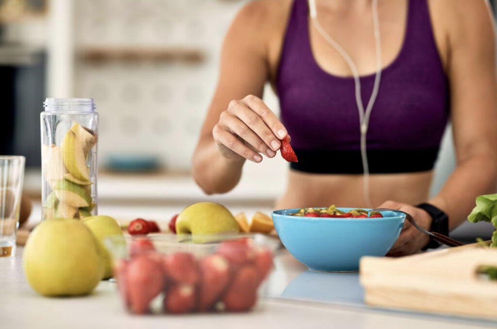 Imagen de apoyo para el texto donde se puede ver una chica preparando un plato de fruta como un hábito saludable