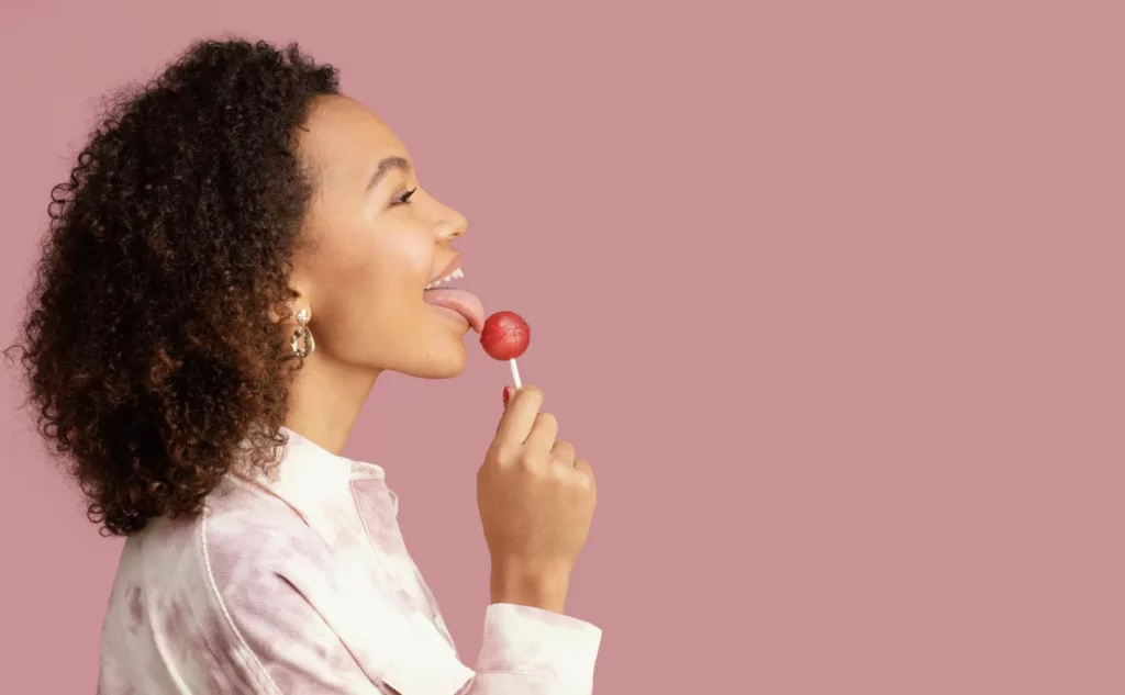 chica disfrutando de comer una paleta de caramelo roja